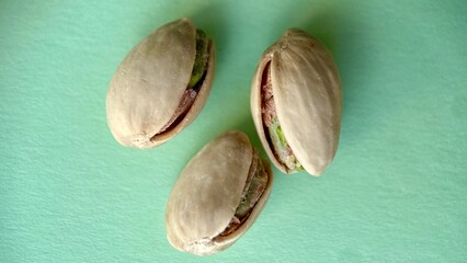 Three pistachios in shells on a light green background