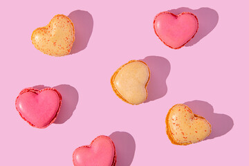 Heart shaped macarons in pink and yellow arranged in a playful pattern