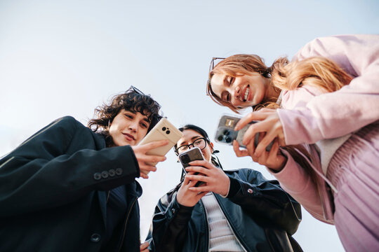 Friends using smartphones on urban street in Seoul from low angle view