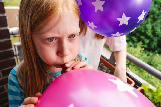Girl inflating balloon with focus and teamwork for party outdoors