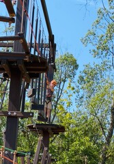 a teenage boy in outdoor rope park passing wooden obstacle course. Active summer holidays