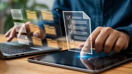 Person interacting with digital documents and files on a laptop and tablet with holographic interface