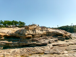 Tourists Exploring the Rocky Plateau of Senjojiki on a Sunny Day in Japan