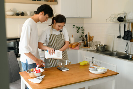 An Asian Couple in casual attire and apron measuring ingredients in a bright, modern kitchen, Homemade baking setup