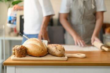 Close-up of Homemade bread loaf and muffins on a wooden tray, set on a wooden table in a bright kitchen setting