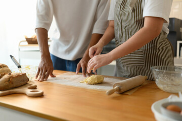 Close-up of a couple preparing cookie dough together, using their hands to knead cookie dough in a cozy kitchen scene