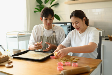 Happy baking moment as a couple shares the task of shaping cookies, Making Cookies Together at Home