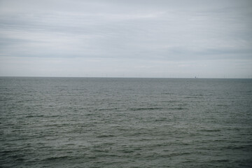 Expansive view of a dark, rippling sea under an overcast sky. The horizon is barely visible in the distance, creating a minimalist and moody seascape scene.