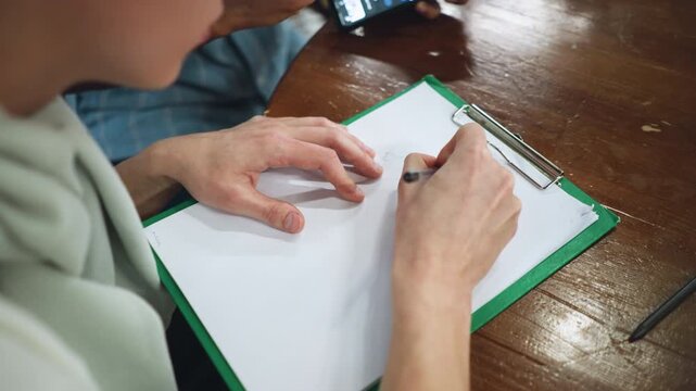 Aerial of hand holding black pen gliding across pristine white paper elegant flowing ink trail captures smooth writing motion under even light focus on subtle finger movements and paper texture