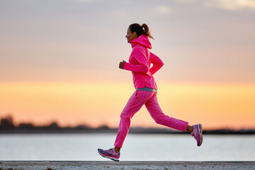 Fototapeta premium woman jogging alone at sunrise, wearing pink running gear, symbolic strength and recovery after breast cancer, nature background, 
