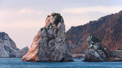 夕日に染まる海岸の岩礁と荒波