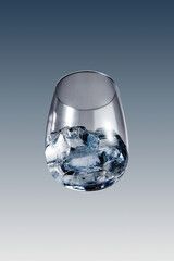Clear Glass Tumbler with Ice Cubes and Cold Water on a Gradient Background