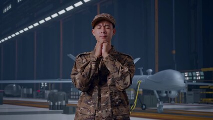 Asian Man Army Soldier Uniform Praying With Modern Military Drone In Maintenance Hangar - Powered by Adobe