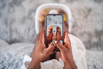 Woman taking photo of feet in foot bath with smartphone