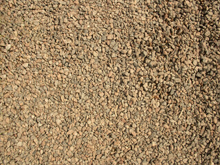 There are a lot of small pebbles and stones on the riverbank on a sunny day. 