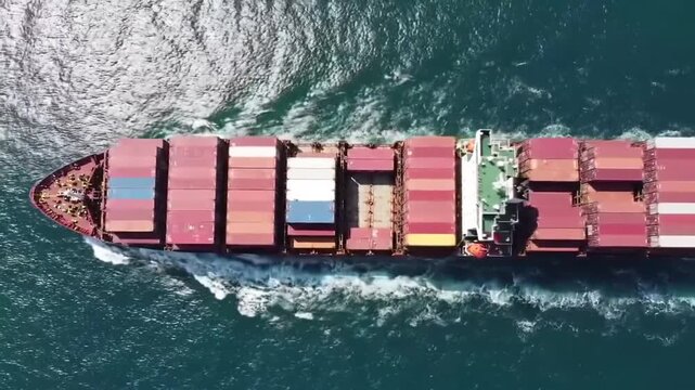 High-angle view of a cargo ship navigating open water, filled with containers.