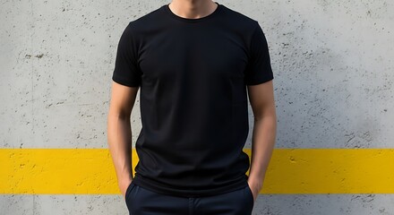 Man wearing a black shortsleeved tshirt against a concrete wall with yellow stripe
