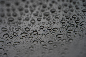 Close-up of raindrops on a window with selective focus. Black and white natural texture for a calm or melancholic mood