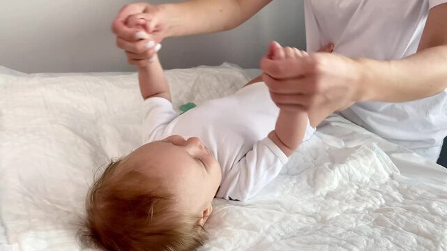 Mother massaging newborn baby,doing arm exercises,bending unbending them.Masseur physical therapist stretching infant child,decreases muscle tone,motherhood,baby care,development,gymnastics