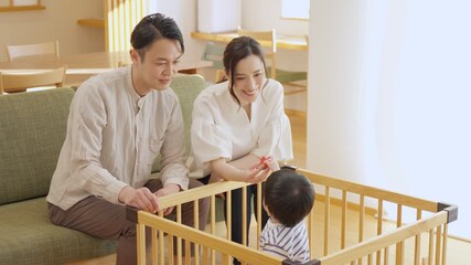 ベビーサークルの中で遊ぶ子供と見守る親