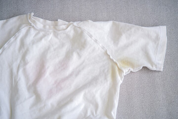 A yellow spot on a white T-shirt. Top view.