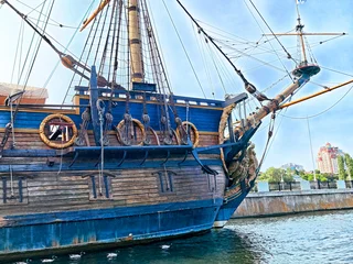 Selbstklebende Fototapeten Schiff Detailed view of a historic wooden ship docked by the waterfront during a sunny day  © keleny