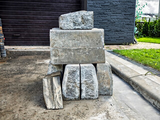 Pile of gray stones arranged on a construction site in a residential area during bright daylight