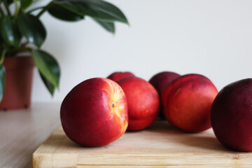 Fresh Ripe Nectarines on Wooden Cutting Board with Plant in Background