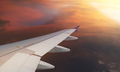 Dramatic view form aircraft window show airplane wing and engine on tropical summer twilight sky and colorful clouds. Image use for travel and transportation background.