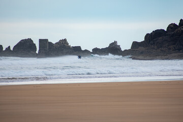 Surfing at Zarautz beach with rugged coastline in the background on a calm morning