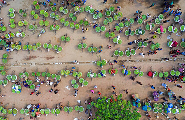 Kansat, Bangladesh - 15 June 2019: Aerial view of a bustling market scene on Sona Masjid Road, where vibrant green produce contrasts with the earthy tones of the ground.