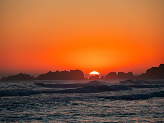 Golden sunset over the rocky coastline of Zarautz with gentle waves lapping at the shore
