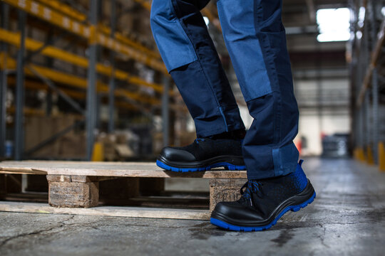 Warehouse Worker in Safety Shoes Standing on Wooden Pallet