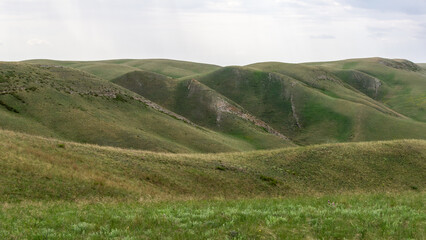 Long mountains. Rolling green hills under a cloudy sky create a serene landscape, showcasing the...
