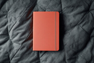 Fototapeta premium A vibrant red notebook with a textured cover and elastic closure, lying open on a dark, textured surface, ready for writing