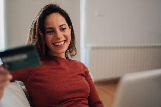 Smiling woman making online payment using credit card and laptop at home