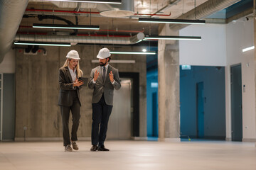Architects walking and discussing in empty office using tablet