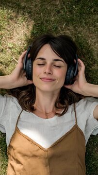 A serene moment captured of a woman lying on the grass with headphones, enjoying the tranquility of nature while listening to music and feeling at peace with herself.