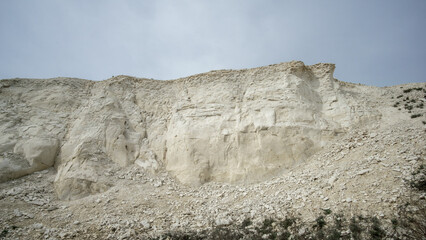 Pokrovsky Cretaceous mountains. White chalk cliff face rises dramatically against a cloudy sky, showcasing natural geological formations and textures in a serene outdoor environment