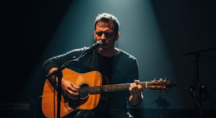 Obraz premium Musician performs solo with acoustic guitar under a spotlight on stage