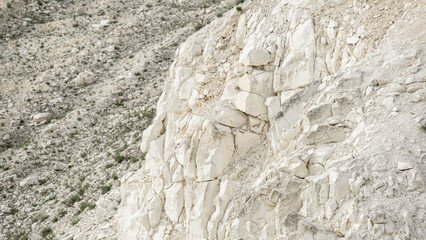 Pokrovsky Cretaceous mountains. Natural rocky cliff face with textured white stone formations and sparse vegetation, showcasing geological features and rugged landscape beauty