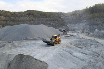 Work of a bulldozer in quarry for the extraction of migmatites and crushed stone.