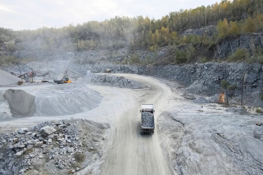Trucks carry migmatite and crushed stone in quarry for the extra