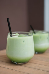 Glasses of iced matcha latte, creamy and refreshing beverage,  on the garden table in summer.