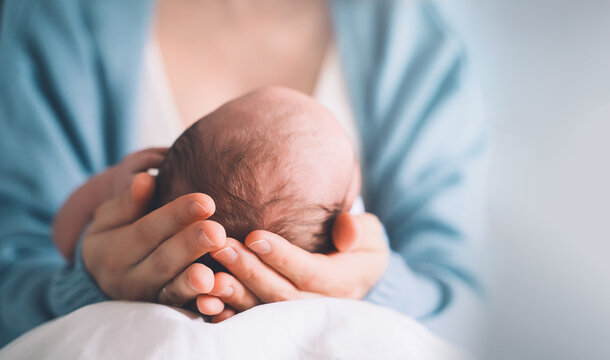 Newborn in mother's hands. Baby care. Childbirth and motherhood concept.
