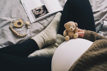Woman pregnant belly with little teddy toy bear. Concept photo with symbol of many meanings for expectant mother during pregnancy and her unborn baby.