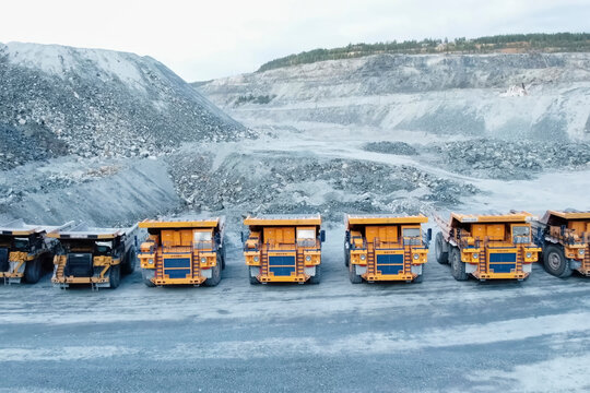 Mining dump trucks are parked in row. Equipment for an industrial quarry.