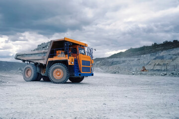 larger mining dump truck in the quarry against the background of rocks. © Olga