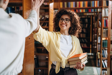 Two women are doing high five in the library