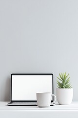 Obraz premium Laptop, mug, and succulent plant on white table. Minimalist workspace with empty screen